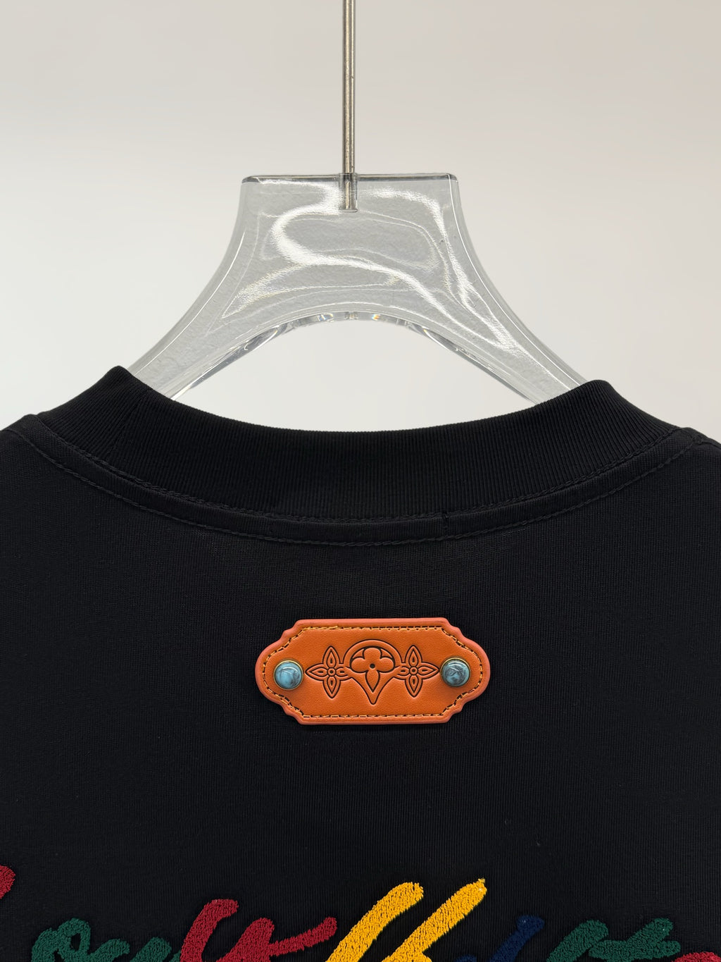 Black short-sleeve shirt neckline with orange logo patch detail