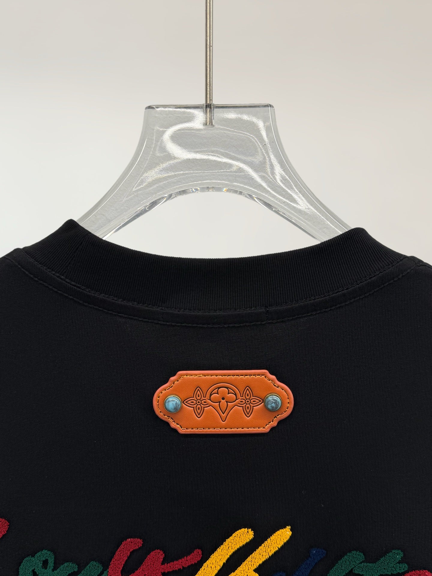 Black short-sleeve shirt neckline with orange logo patch detail