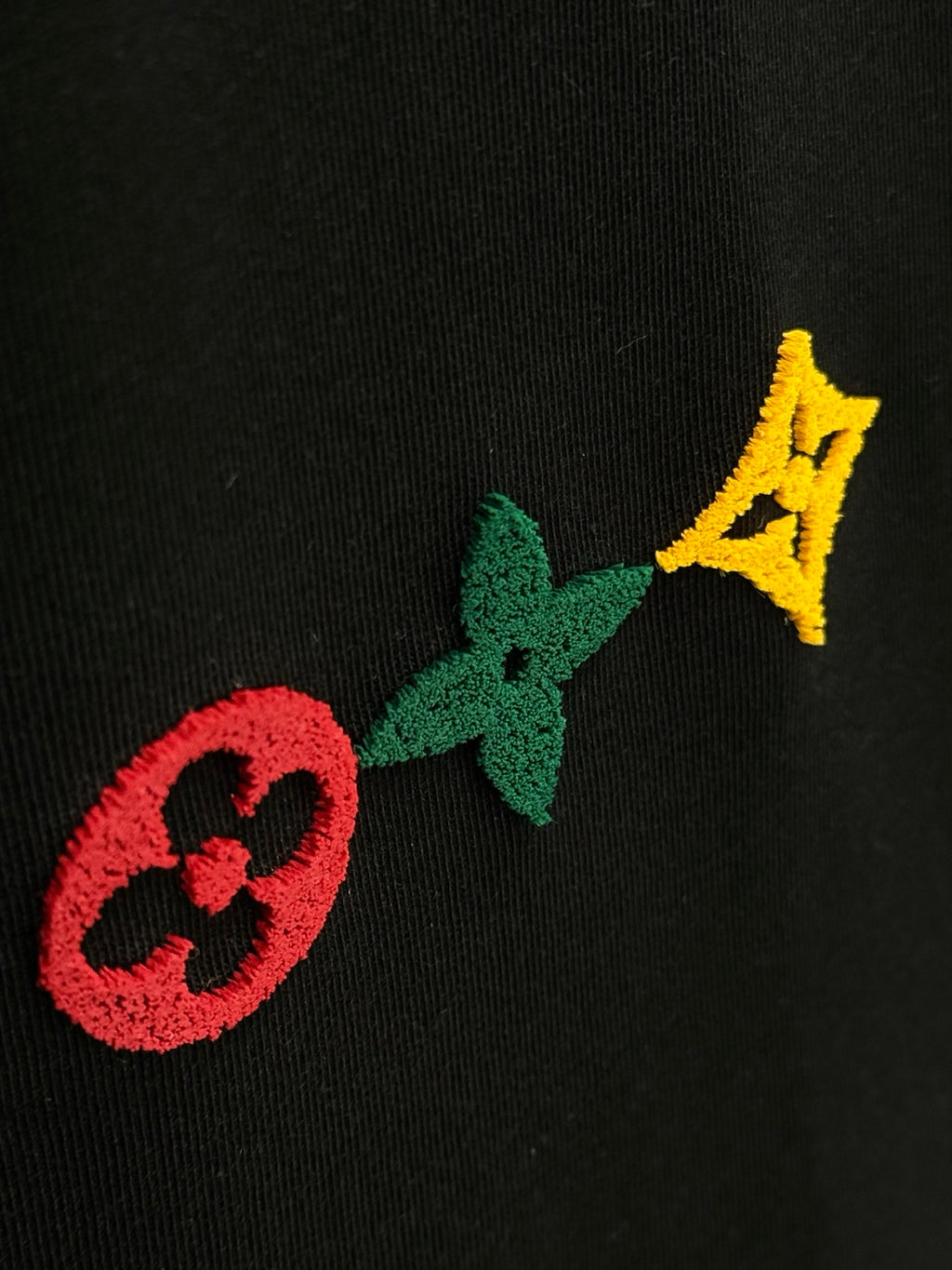 Black knit fabric with red, green, and yellow logo emblem details