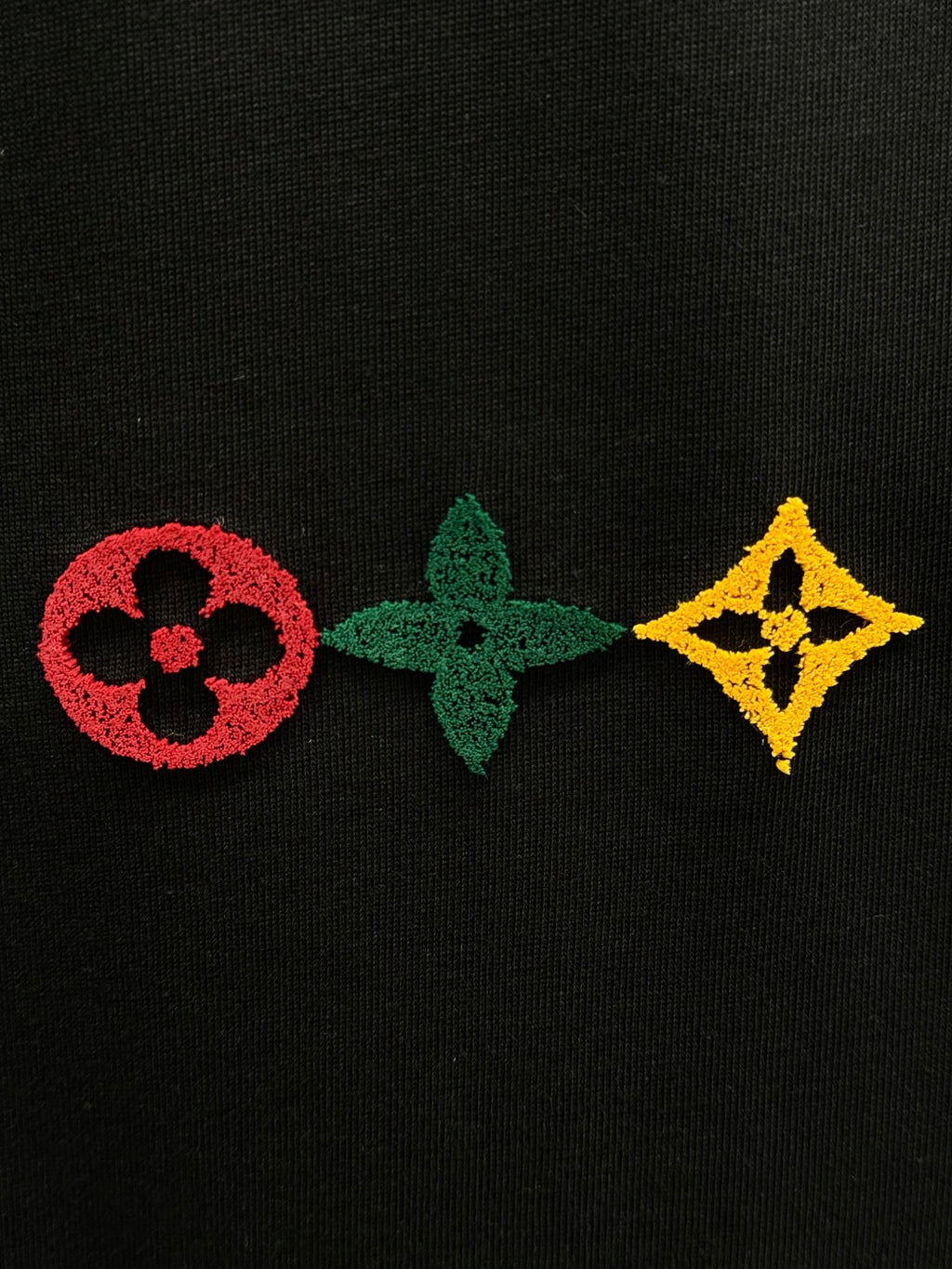 Black knit fabric with red, green, and yellow emblem patches