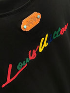 Black short-sleeve shirt with orange logo patch and red cursive print