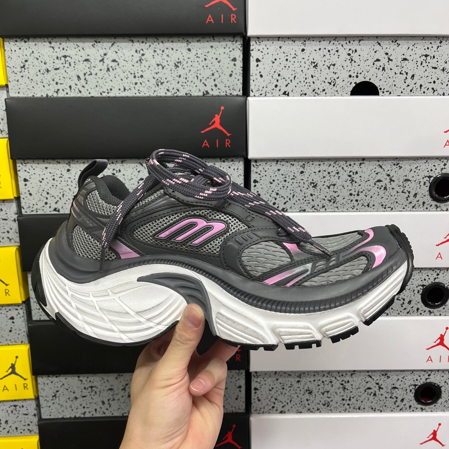 Unisex running sneakers on box, dark gray upper with pink accents and white sole