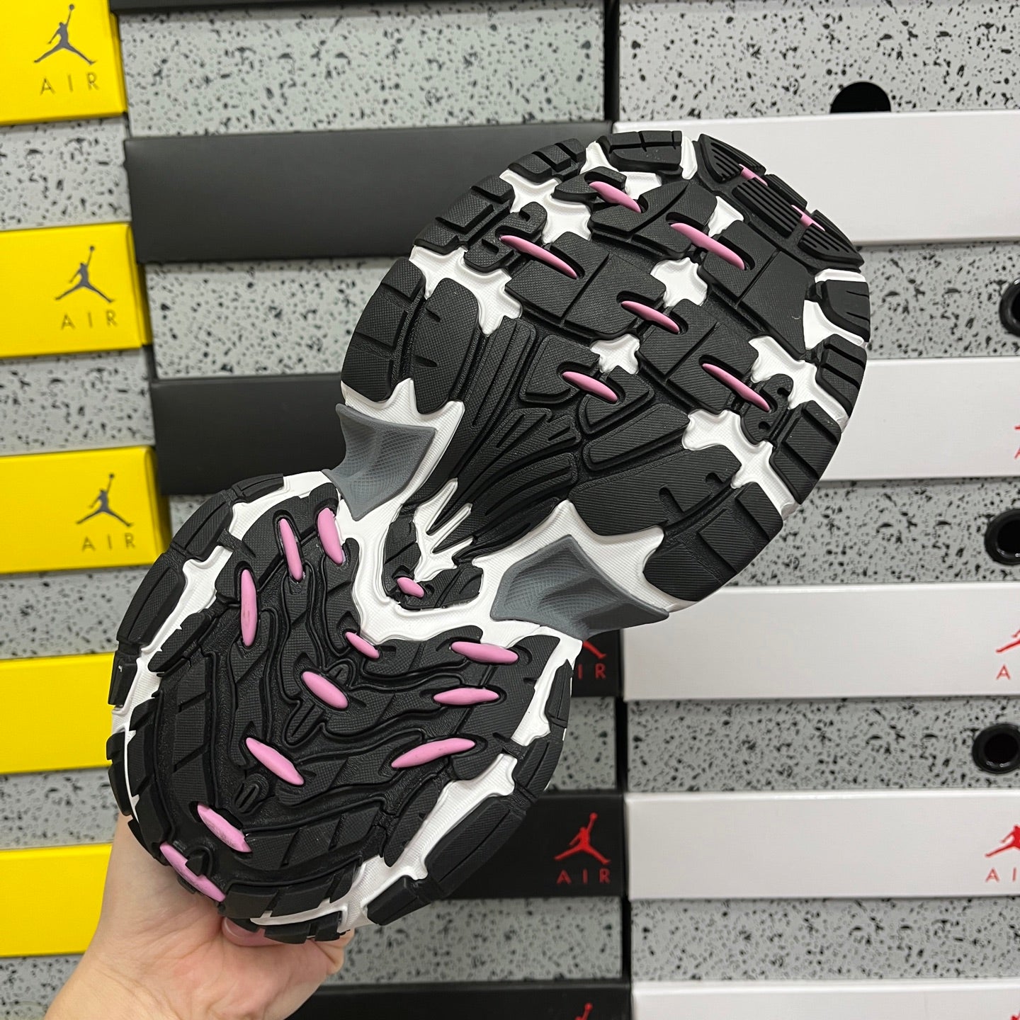 Unisex sneaker outsole in black and gray with pink accents and tread pattern