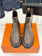 Louis Vuitton monogram chelsea boots facing forward with black elastic panels and white edge stitching