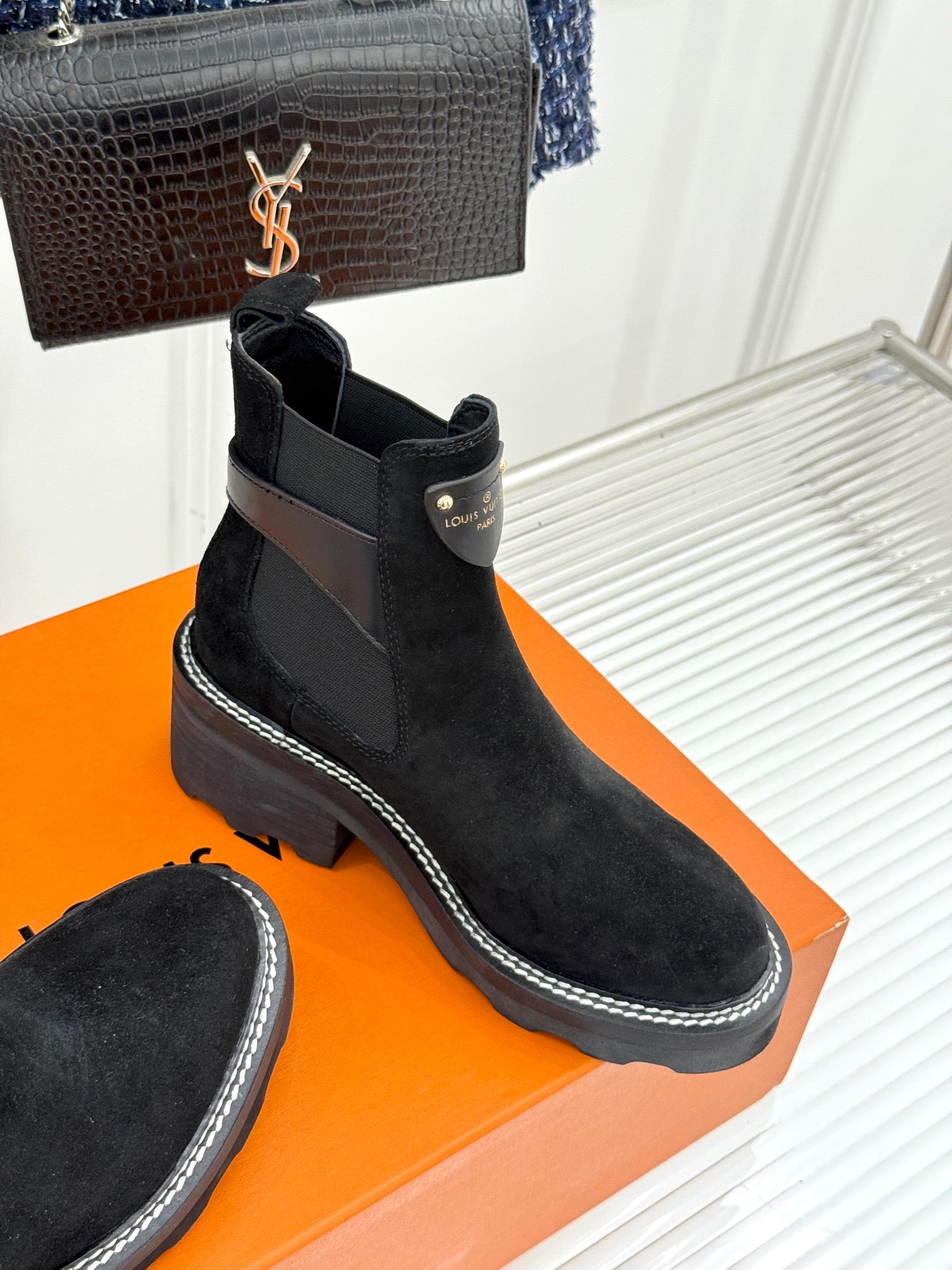 Black suede ankle boots with dark logo patch and contrast-stitched sole edge