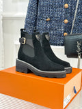 Black suede ankle boots with side elastic, buckle strap, and tread sole