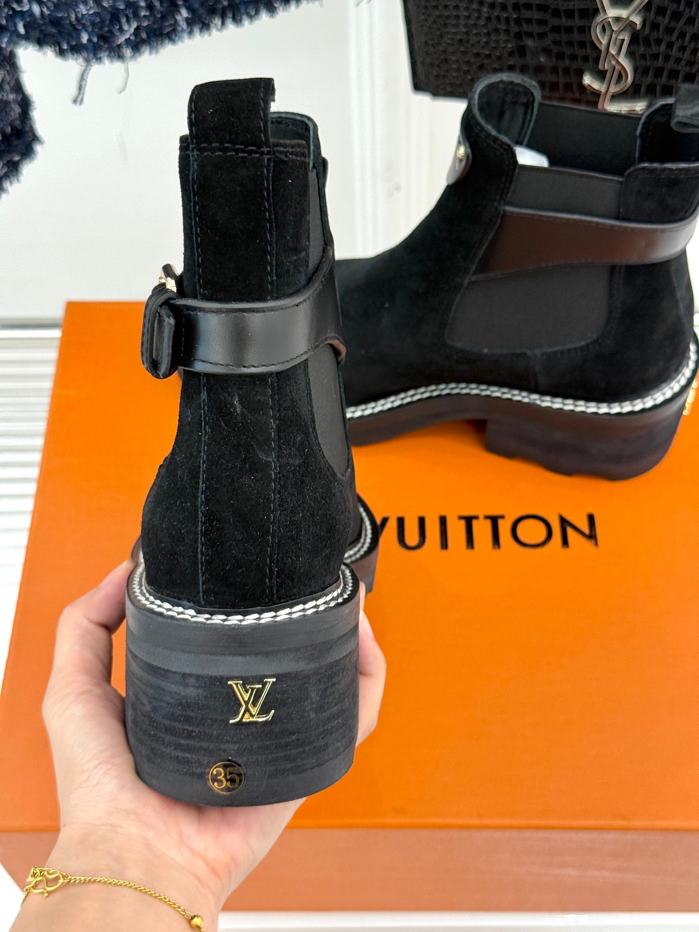 Black suede ankle boots with heel pull loops and embossed logo on sole