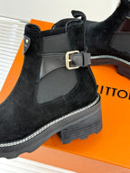 Close-up of black suede ankle boot with gray buckle strap and contrast stitching