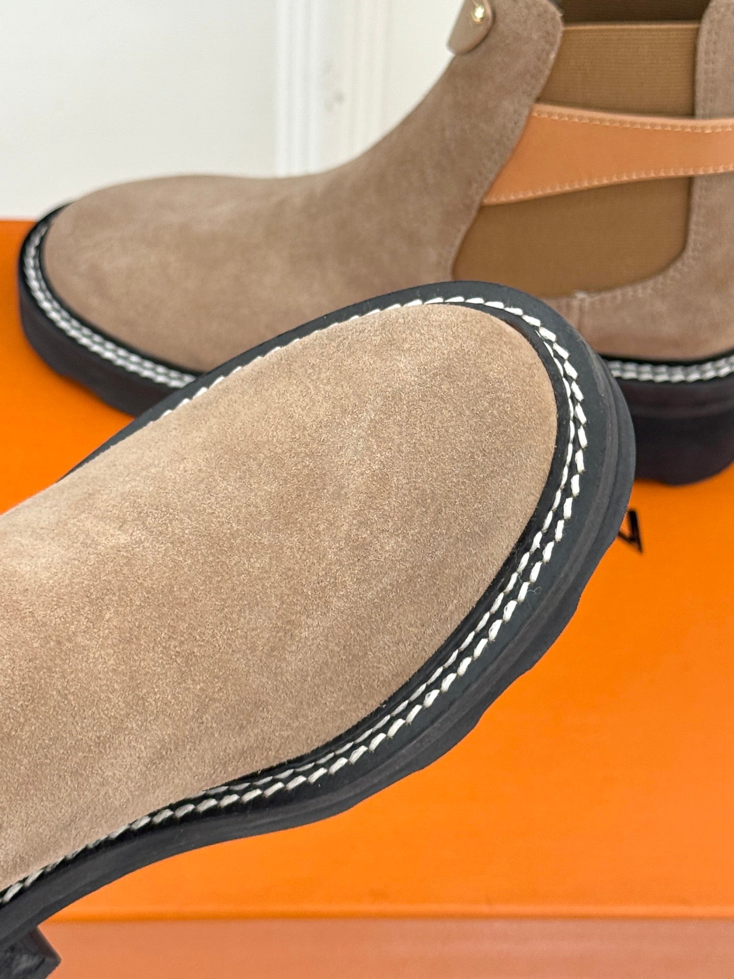 Beige suede ankle boot with stitched edge trim and dark sole