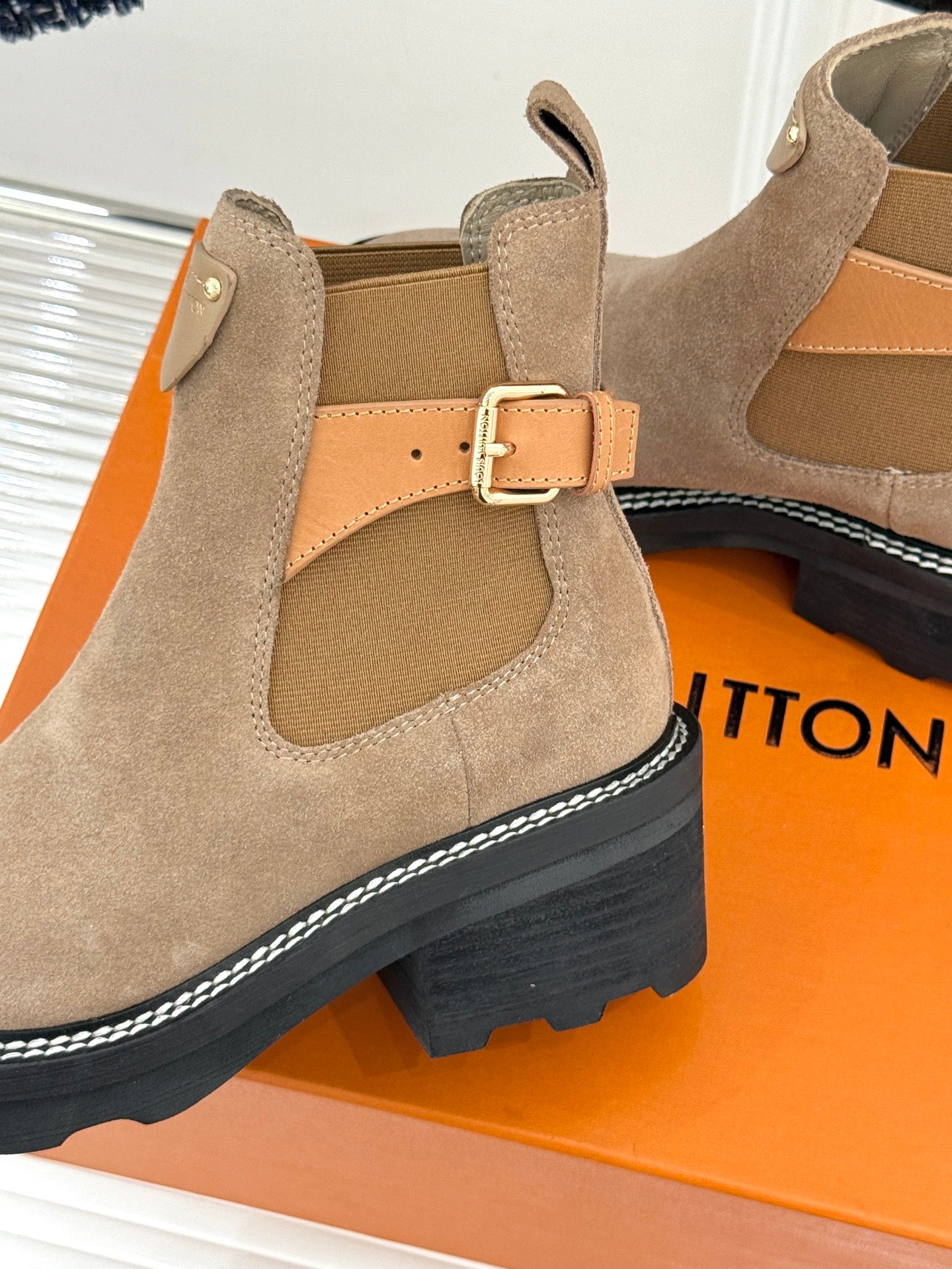 Beige suede ankle boot close-up with buckle strap and padded inner lining