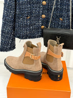 Beige suede ankle boots with buckle strap and black topstitching around sole