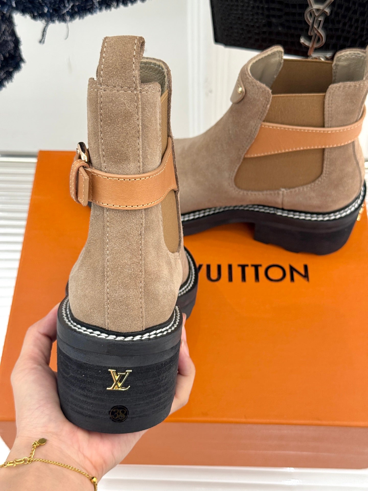Beige suede ankle boots with strap, pull-on collar, and logo on heel