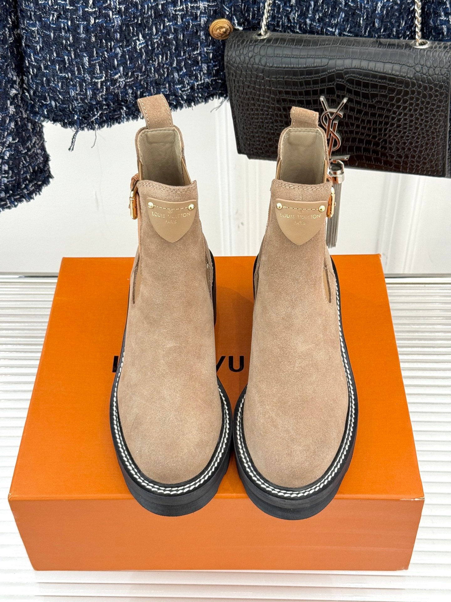 Two beige suede ankle boots with buckle strap and dark ribbed sole