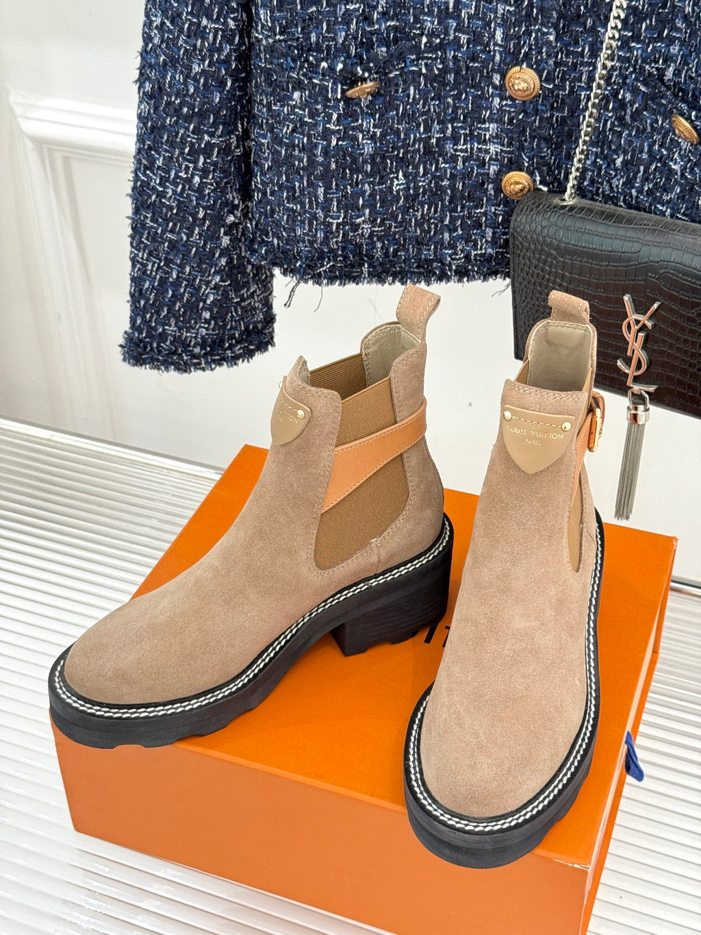Pair of beige suede ankle boots with buckle strap and dark rubber sole