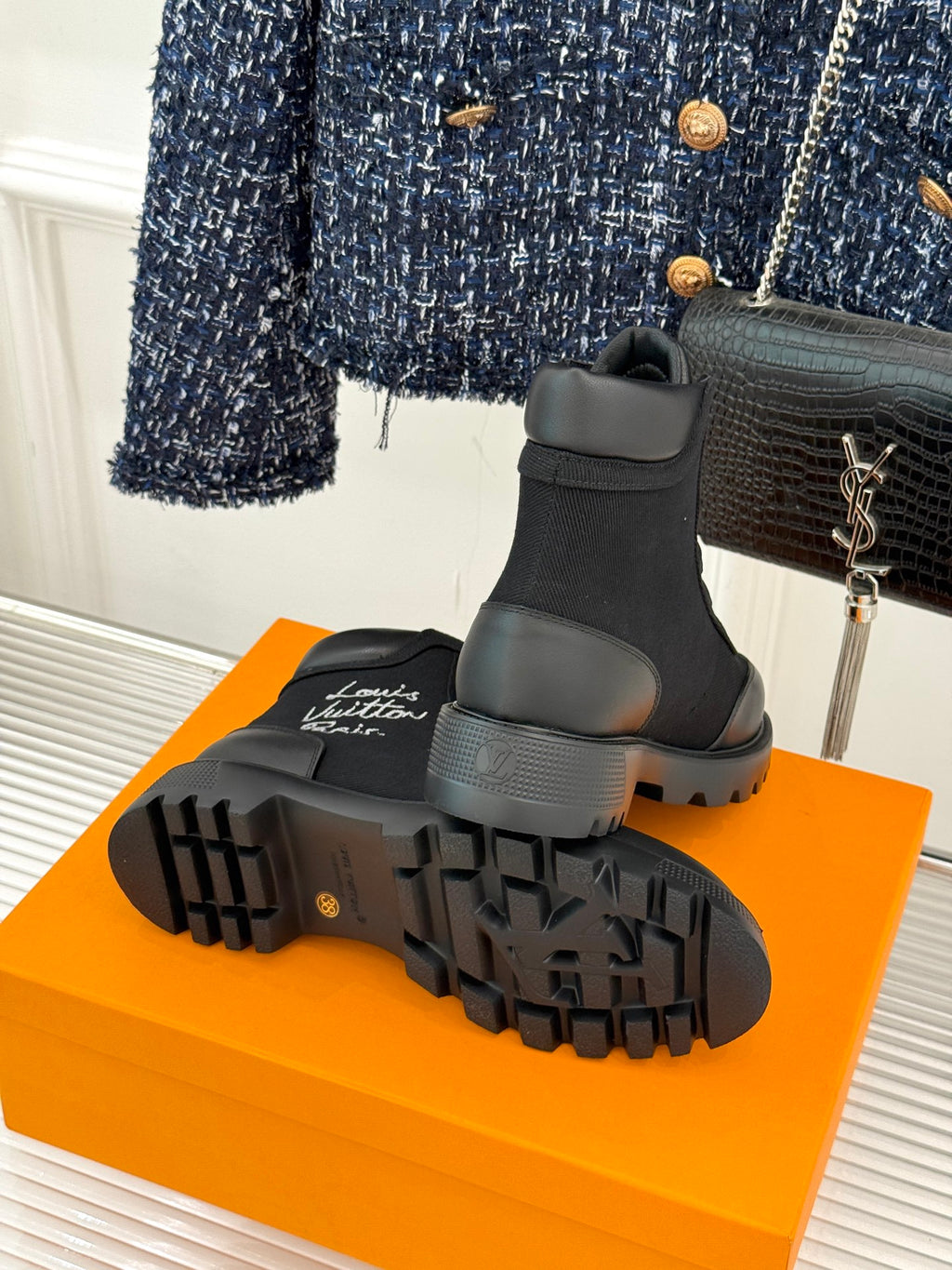 Black mid-top lace-up boot outsole view with deep lug tread and logo detail