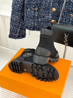 Black mid-top lace-up boot outsole view with deep lug tread and logo detail