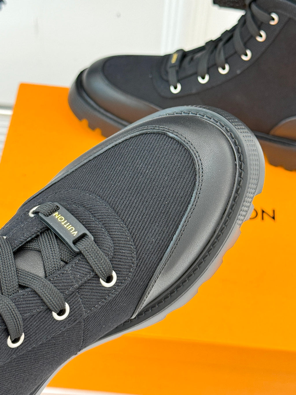 Black lace-up mid-top boot close-up with textured cuff and thick rubber sole