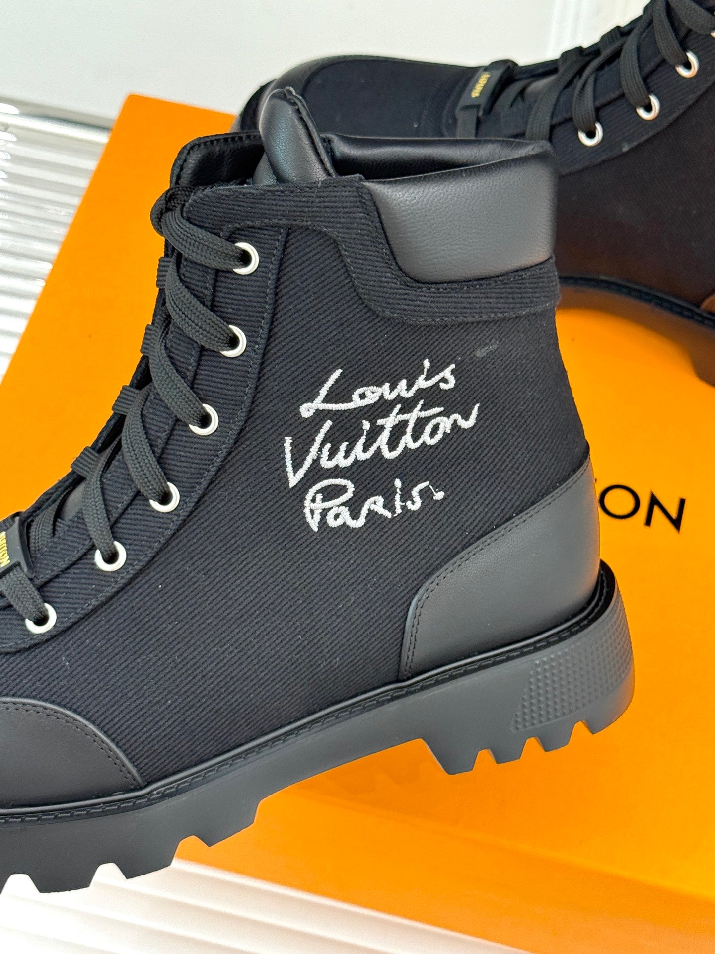 Black mid-top lace-up boot close-up with Louis Vuitton Paris logo on upper