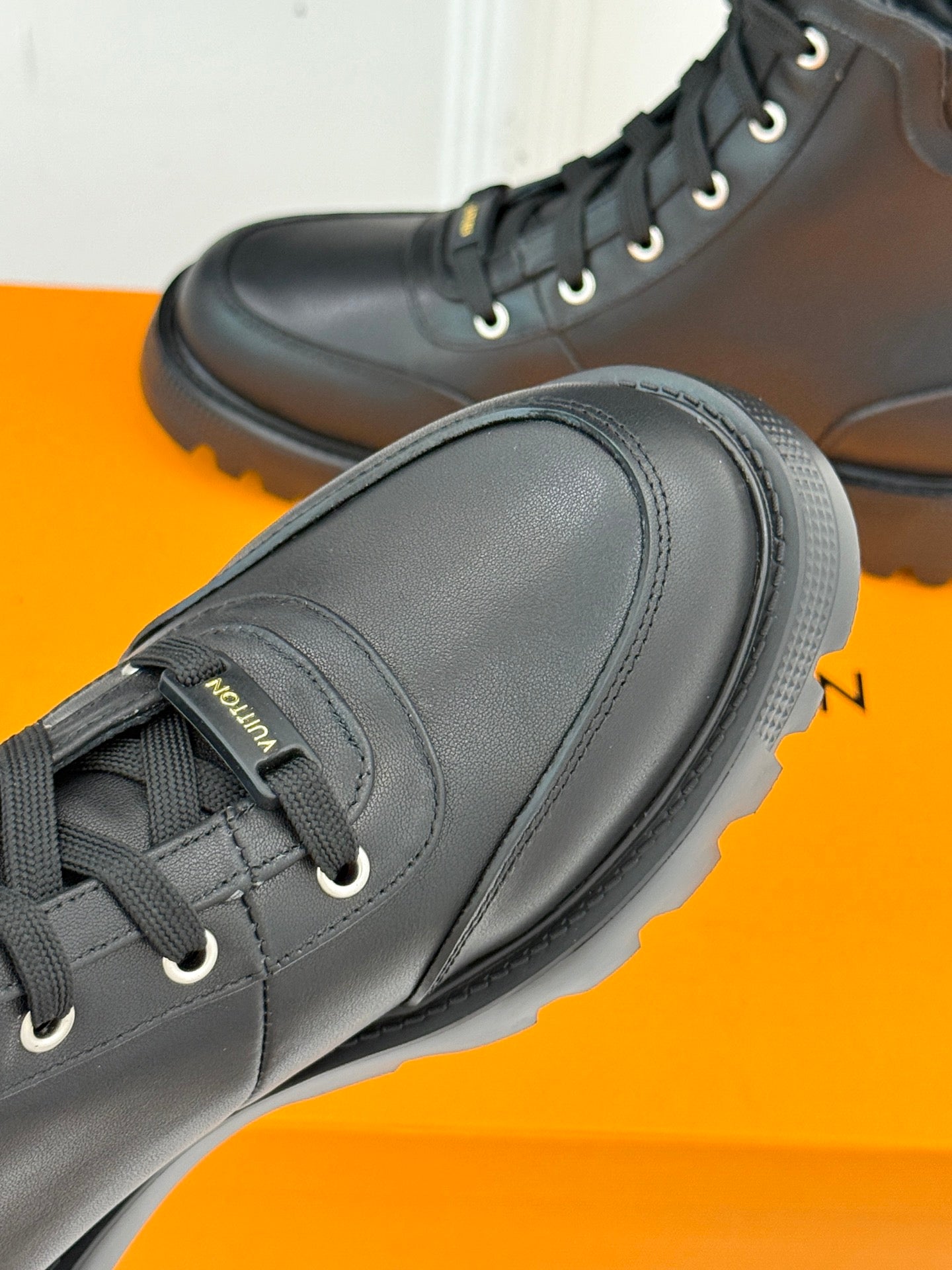 Black leather lace-up boot toe with textured rubber sole and laces