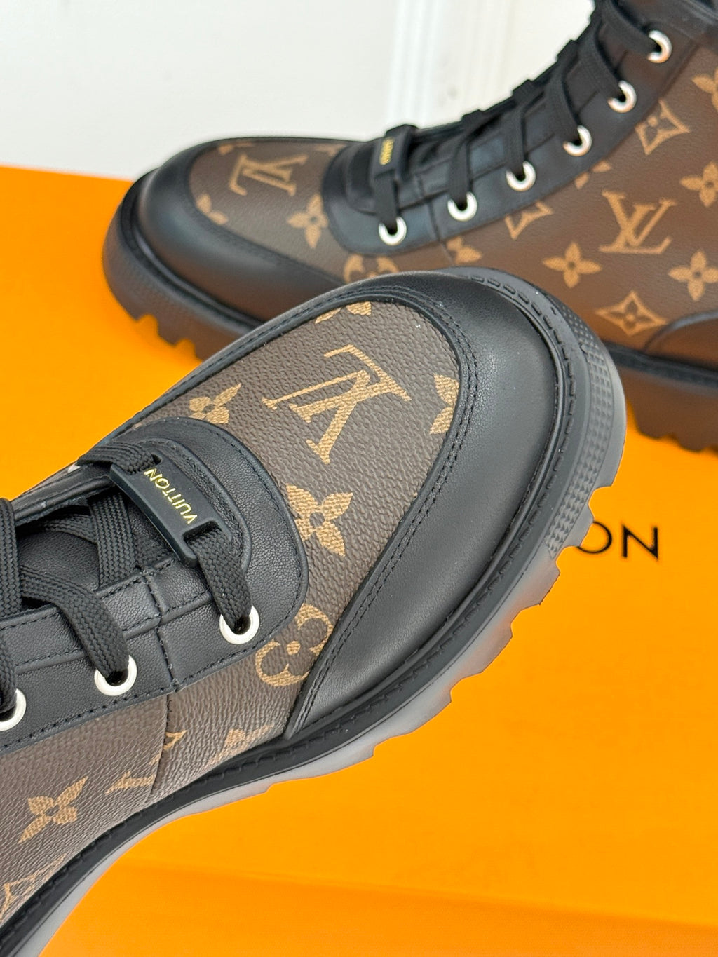Side view monogram lace-up boots, brown upper with black trim and thick tread sole