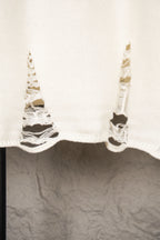 White knit sweater hem with frayed sleeves and cutout stitching