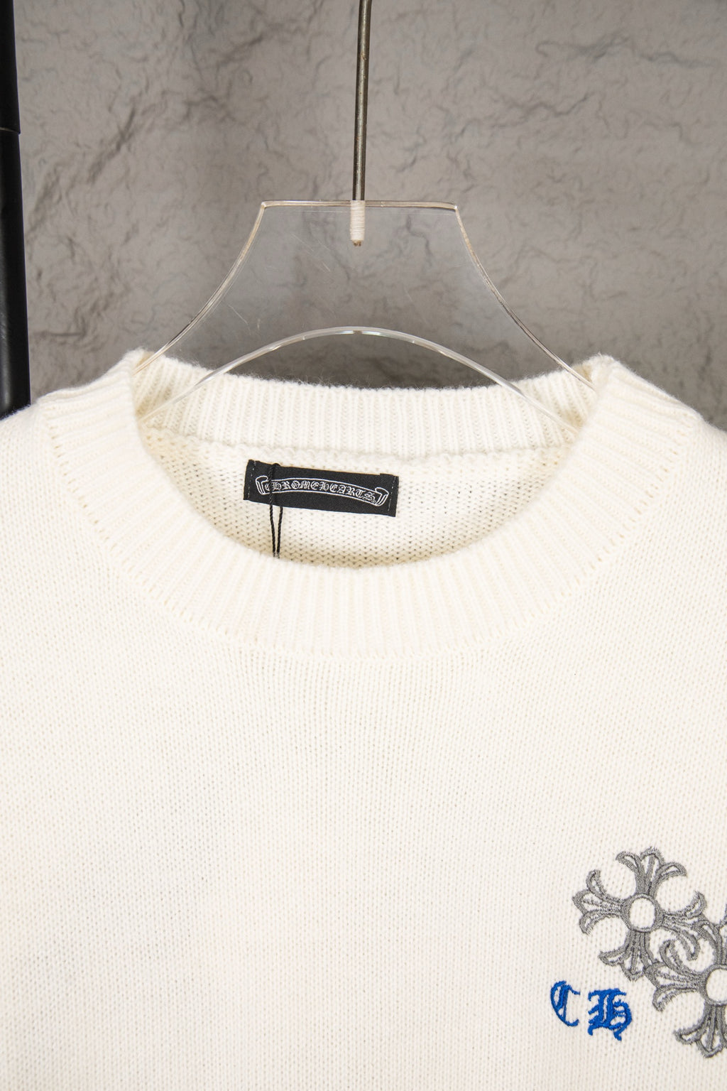 White knit sweater neckline with brand label and small right-chest crest