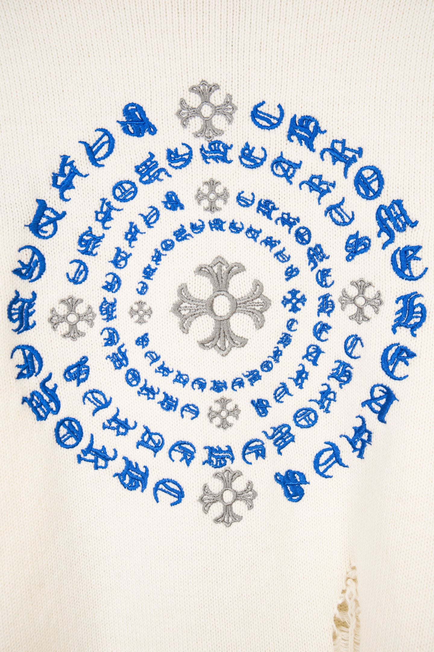White knit sweater back close-up of blue pattern and gray flower