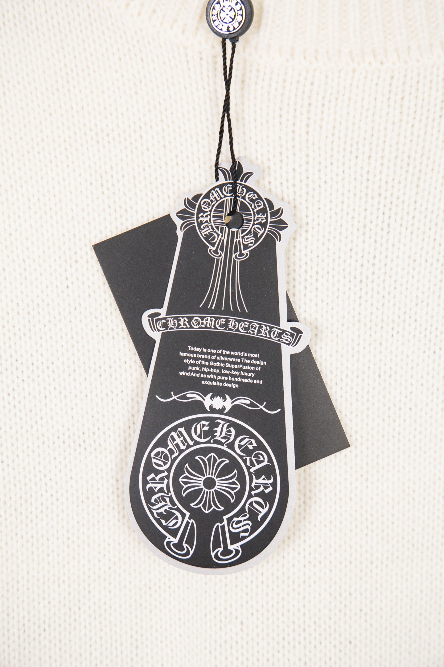 White knit sweater front tag graphic with ornate crest and text