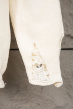 White knit sweater cuff with frayed stitched cutout detail