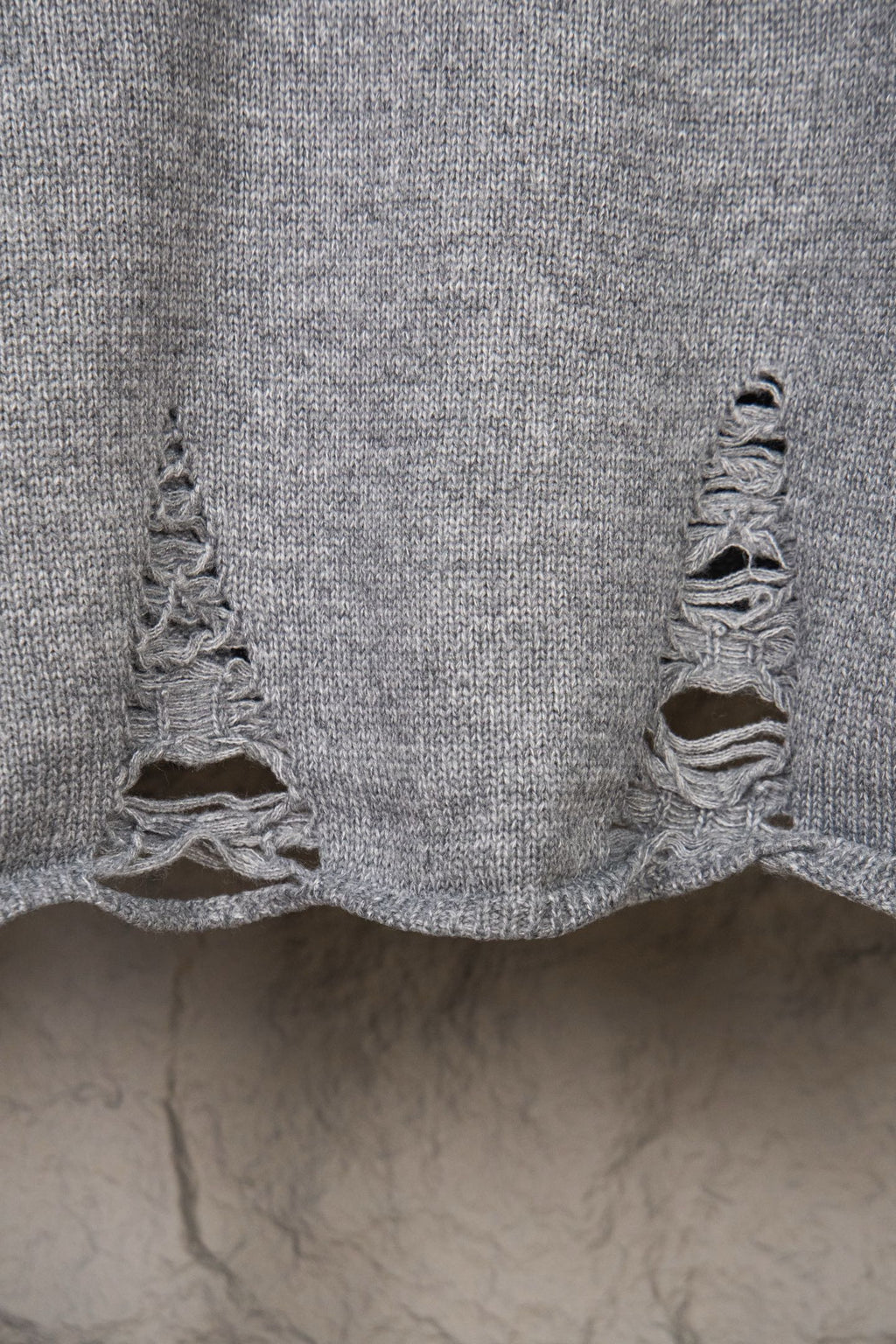 Grey knit sweater bottom hem with ruffled knitted edge detail