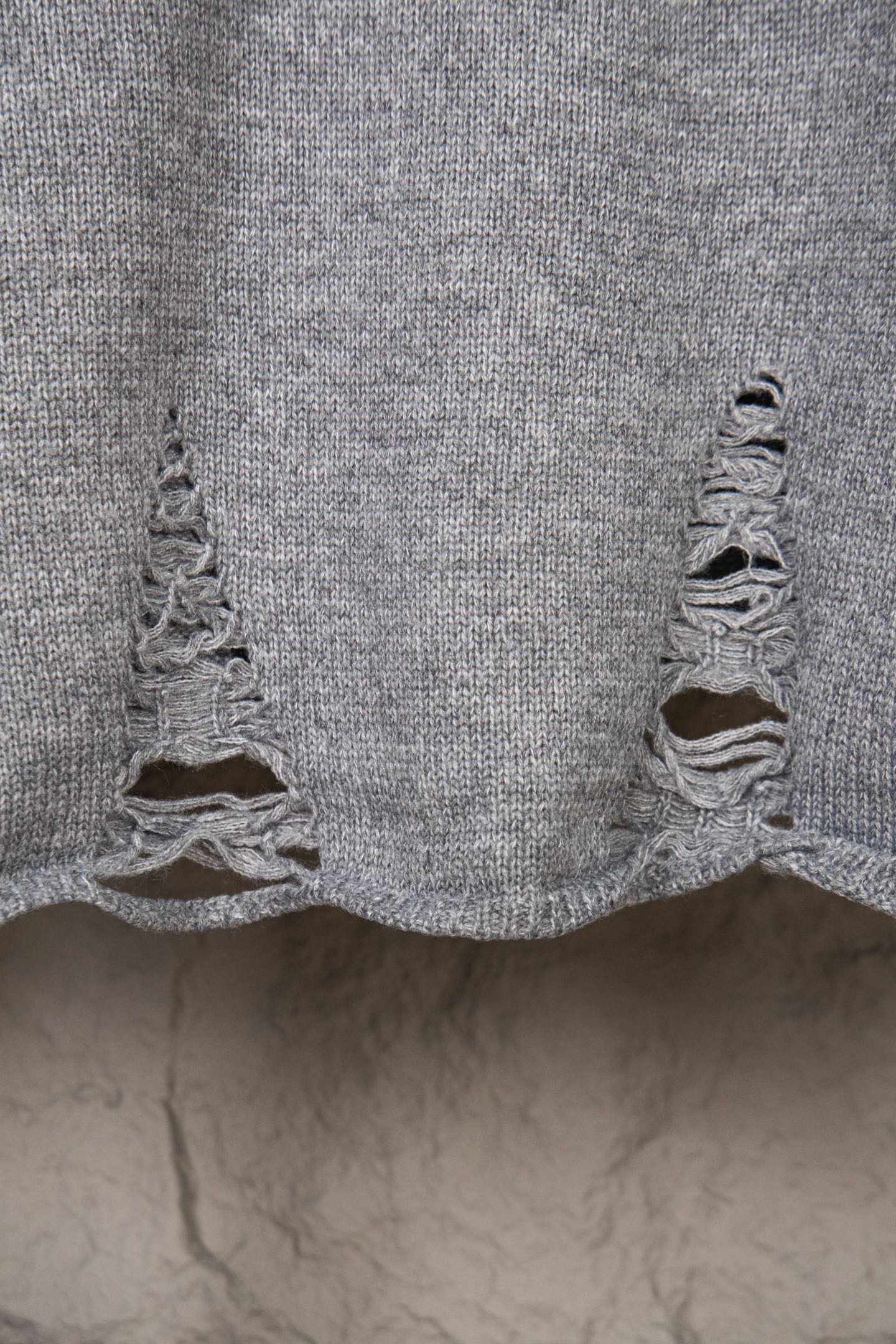 Grey knit sweater bottom hem with ruffled knitted edge detail