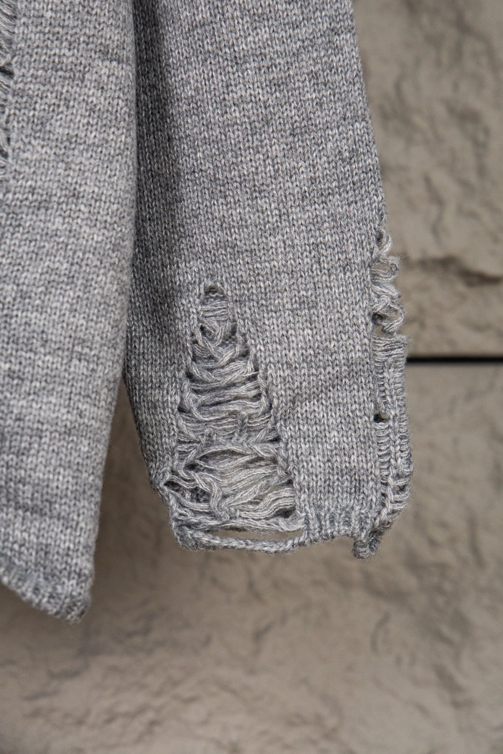 Grey knit sweater hem with decorative braided stitching