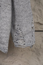 Grey knit sweater hem with decorative braided stitching