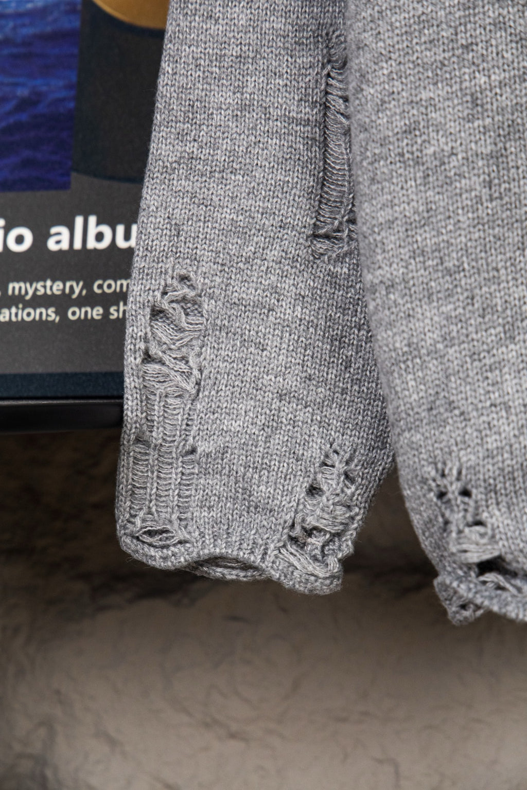 Grey knit sweater sleeve with textured cable-knit cuff detail