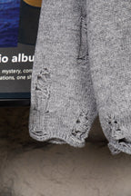 Grey knit sweater sleeve with textured cable-knit cuff detail