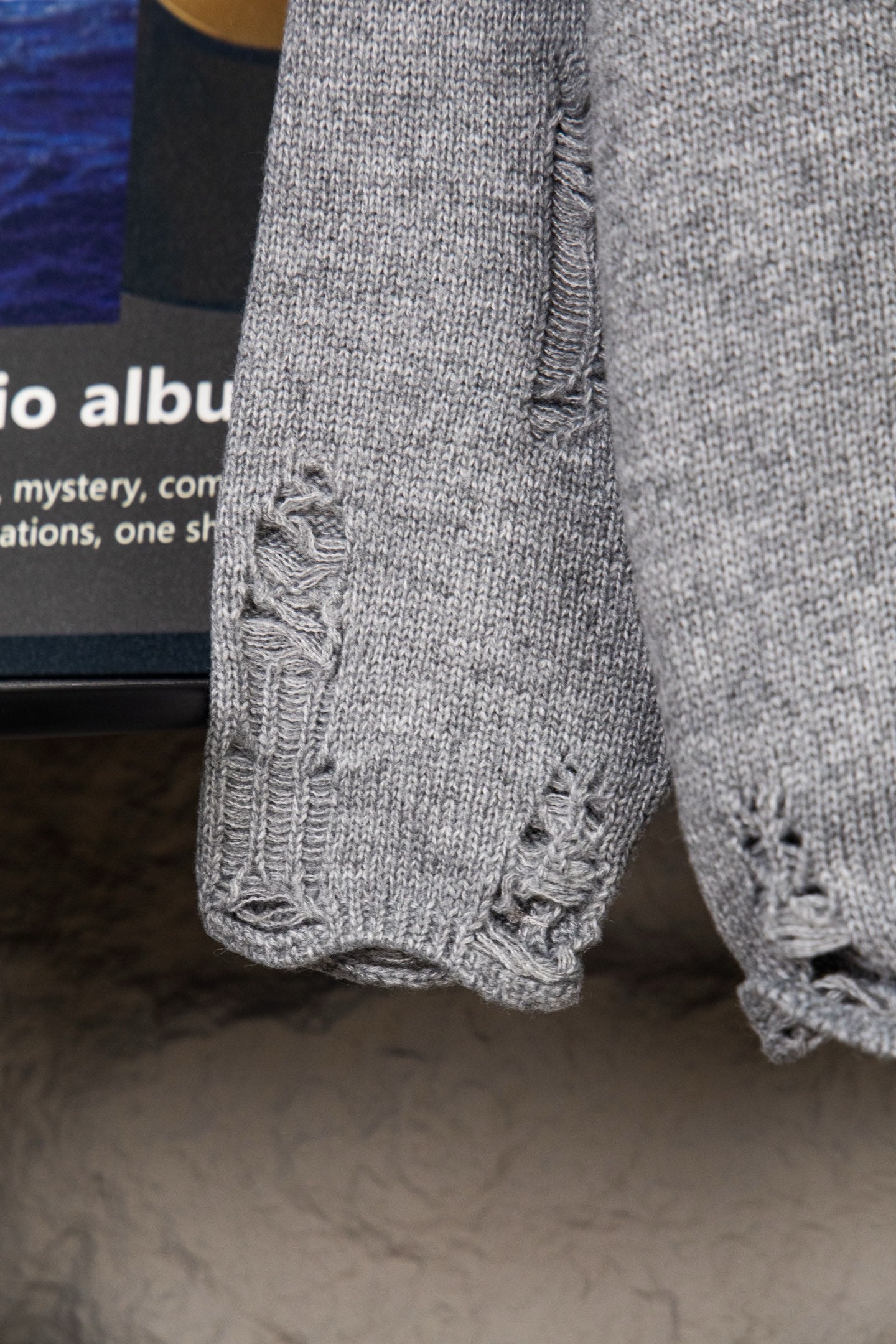 Grey knit sweater sleeve with textured cable-knit cuff detail