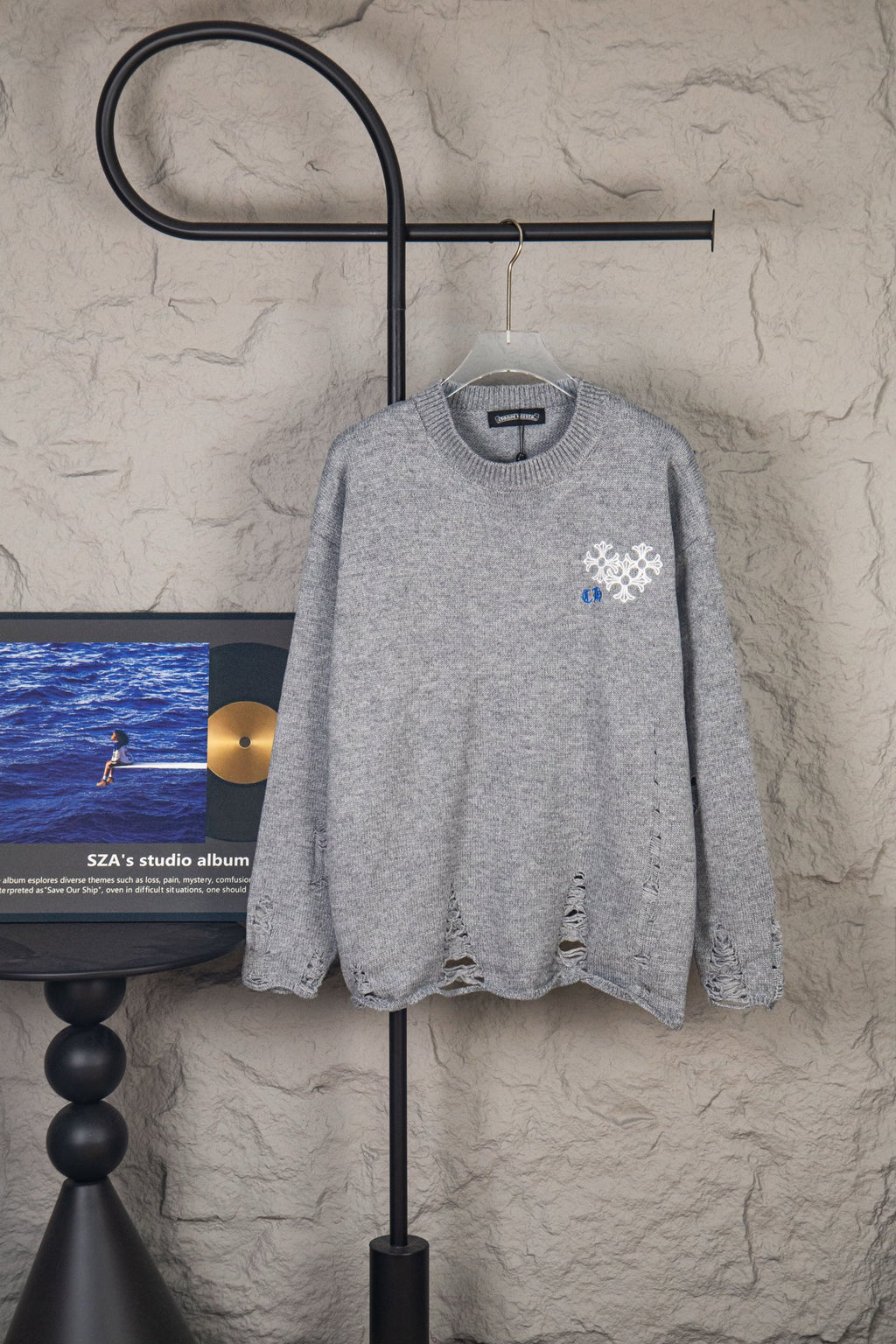 Grey knit sweater with blue and white snowflake-style logo on chest