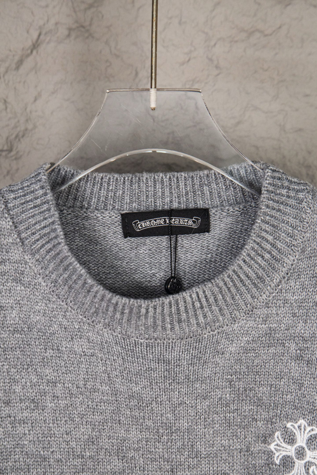 Grey knit sweater neckline with small chest logo detail