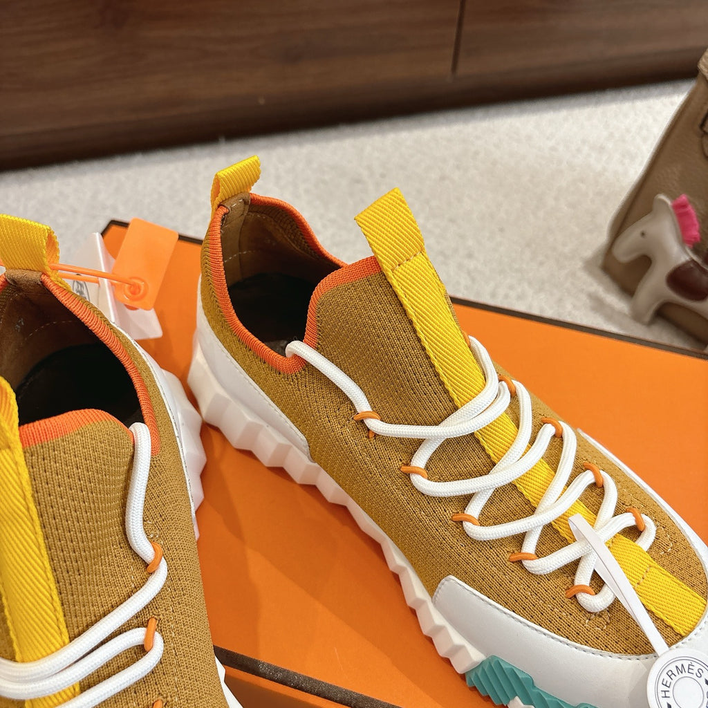 Hermes unisex sneakers close-up side, mustard and brown knit, white laces, teal sole.
