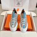Luxury unisex sneakers with grey uppers, blue accents, white laces, and chunky white sole