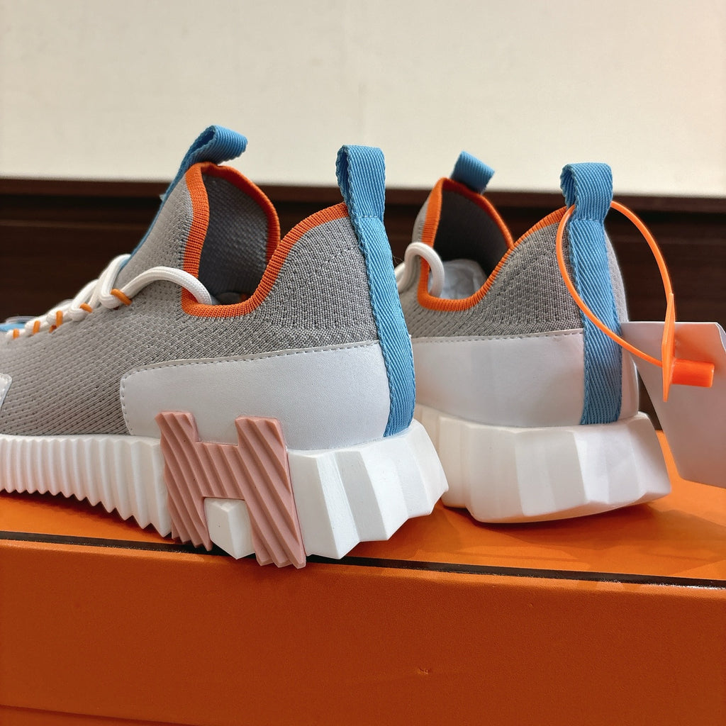 Rear view of unisex luxury sneakers: grey uppers with blue heel loops and chunky sole