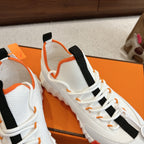 White sneakers close-up with black ankle straps, orange piping, lace-up front