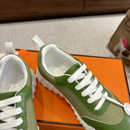 Green Hermes unisex sneaker view with white laces and logo coin detail
