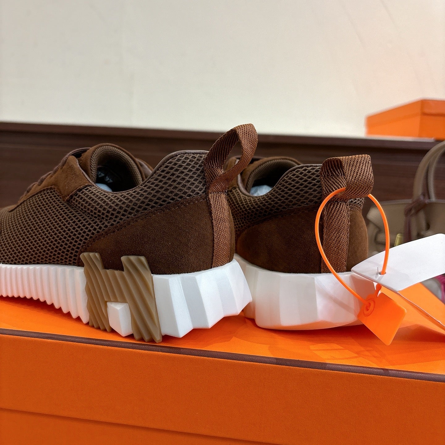 Brown mesh sneaker heels with white ridged soles, close-up from behind.