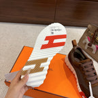 Brown mesh sneaker outsole view with white tread and red accent pattern.