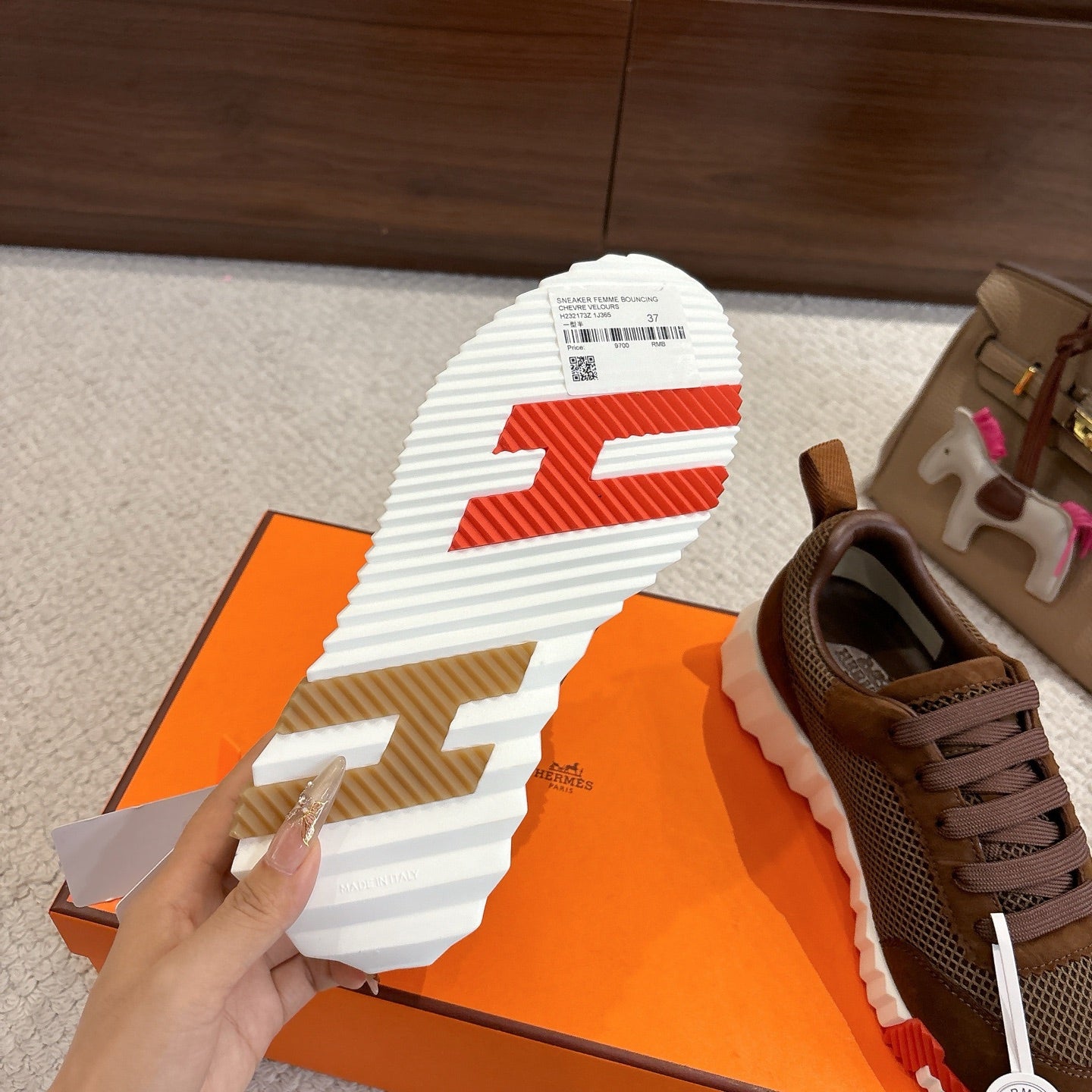 Brown mesh sneaker outsole view with white tread and red accent pattern.