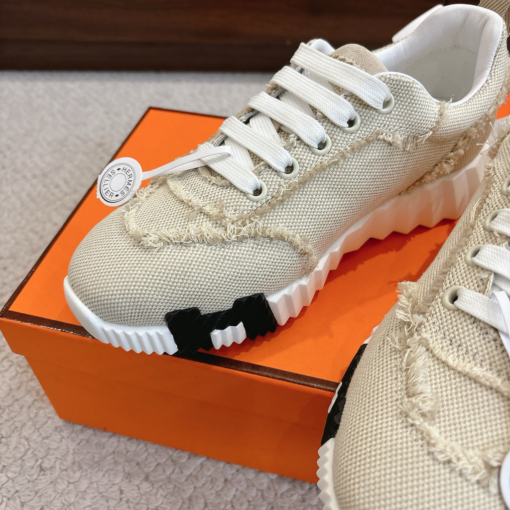 Hermes beige sneakers close-up: white laces, knit texture, and chunky white tread sole