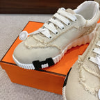 Hermes beige sneakers close-up: white laces, knit texture, and chunky white tread sole
