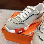 Hermes sneakers close-up: light mesh with navy trim, white laces, textured tread sole.