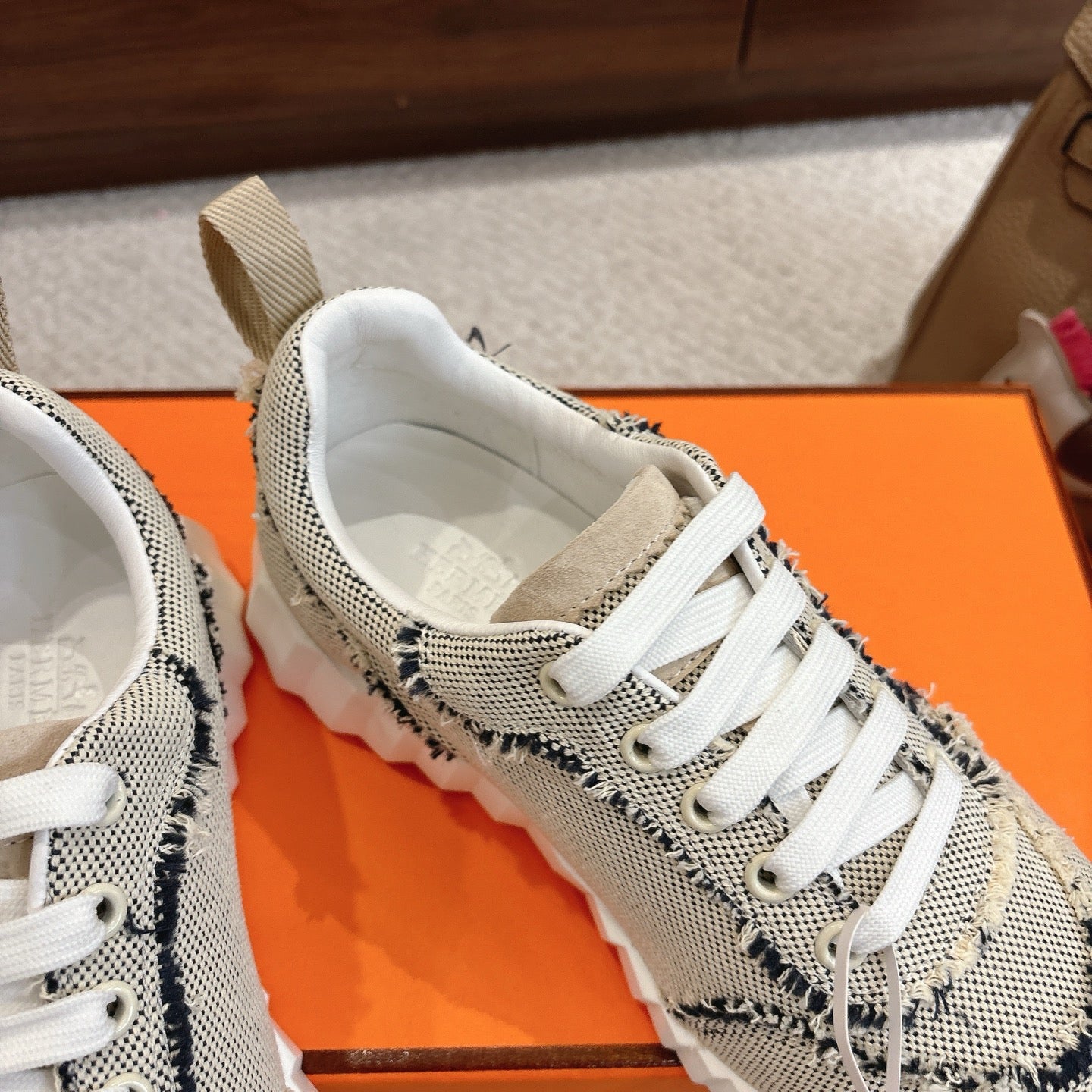 Hermes sneakers with light mesh upper, navy stitched panel, white lace-up, padded collar.